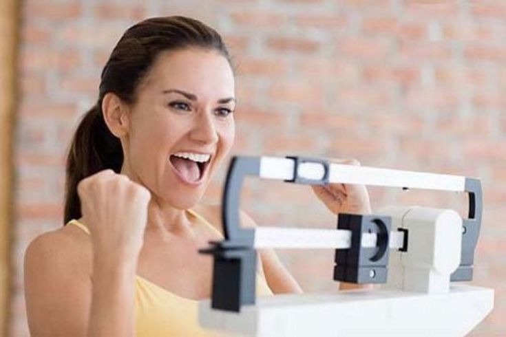 Woman celebrating weight loss success on scale